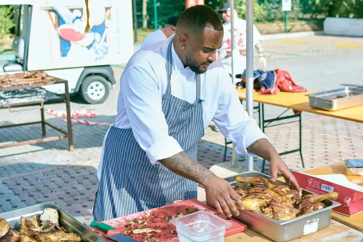 Chef demonstrating cooking techniques at an outdoor food festival with audience