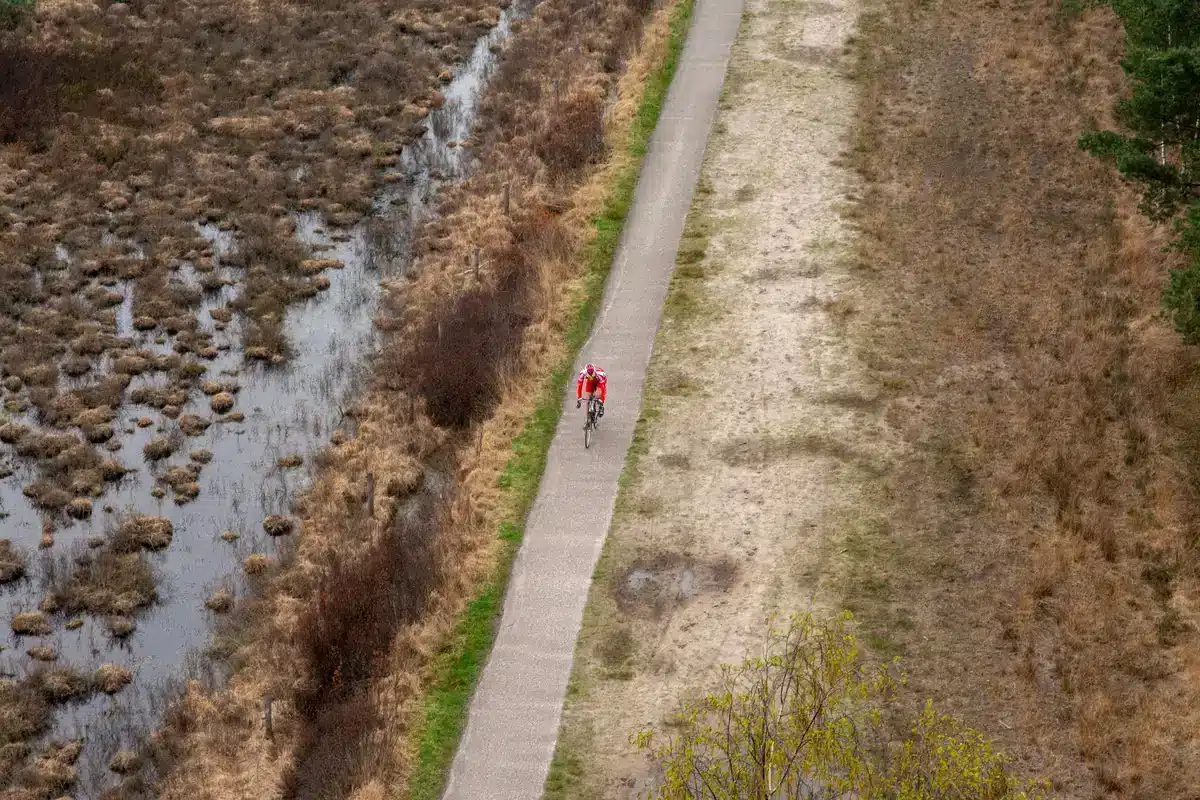 Cyklist på gheal ghlas i bhfearann tuaidh na hÉireann, timpealaithe ag fothain ghlas agus spéir gheal