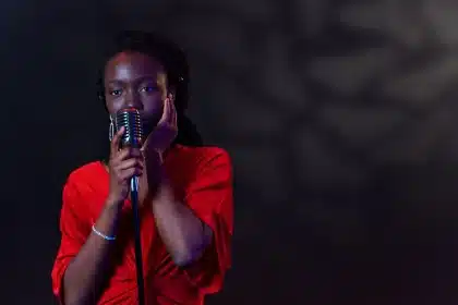 A performer on stage with microphone addressing an audience in a comedy venue