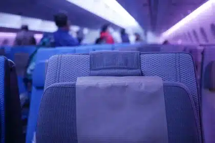 A tired passenger resting in an airplane cabin seat with meal trays and water bottles nearby