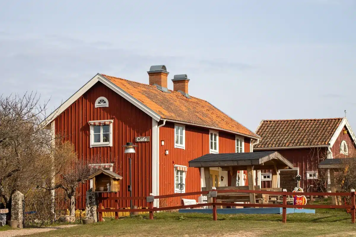 A quiet country road leading to a small village with a café glowing warmly among rural surroundings