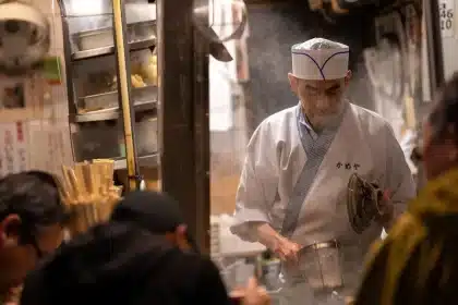 A chef in professional whites plating a refined dish in an elegant fine-dining kitchen