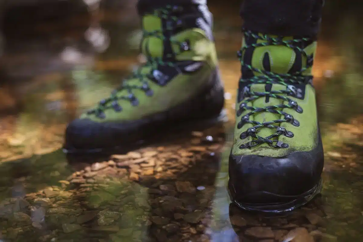 Essential hiking gear including sturdy boots, waterproof jacket and water bottle on outdoor terrain