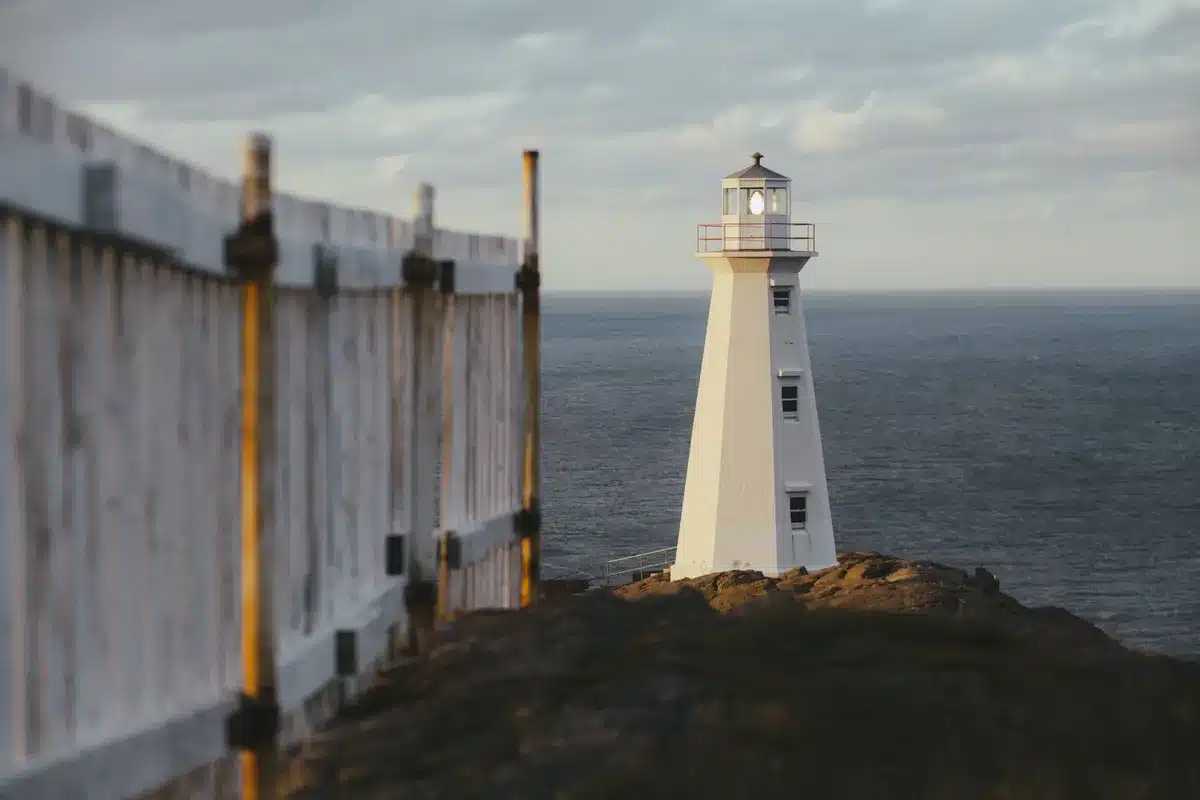 Lighthouse standing on dramatic Atlantic coastline at dusk