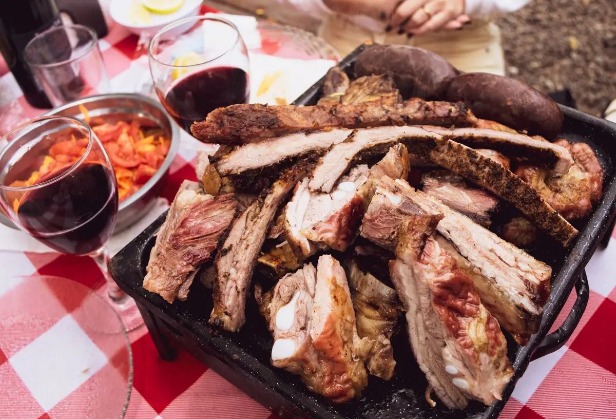 Glass of Spanish red wine served with grilled meat and outdoor barbecue setting