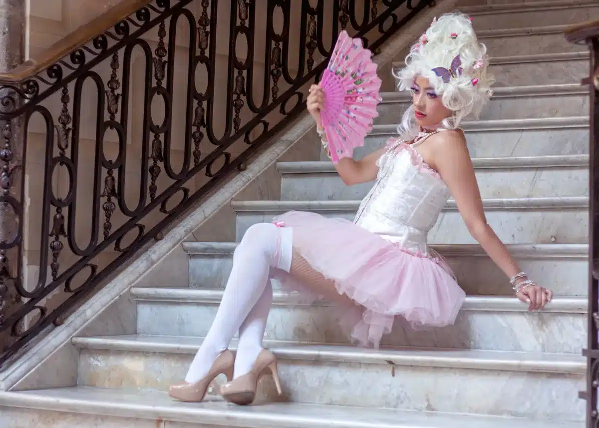 Woman wearing a white lace corset mini dress with white heels and a veil