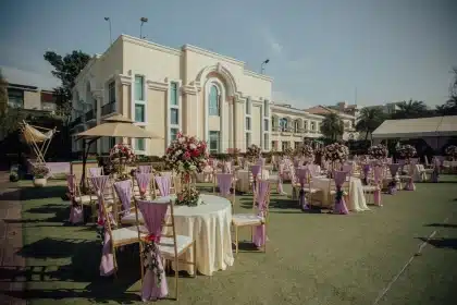Couple exchanging vows at an outdoor wedding ceremony on a sunny lawn with guests seated nearby.