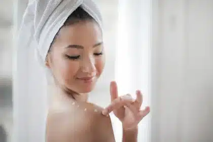 Person applying gentle body lotion to arm in calm, minimalist wellness setting