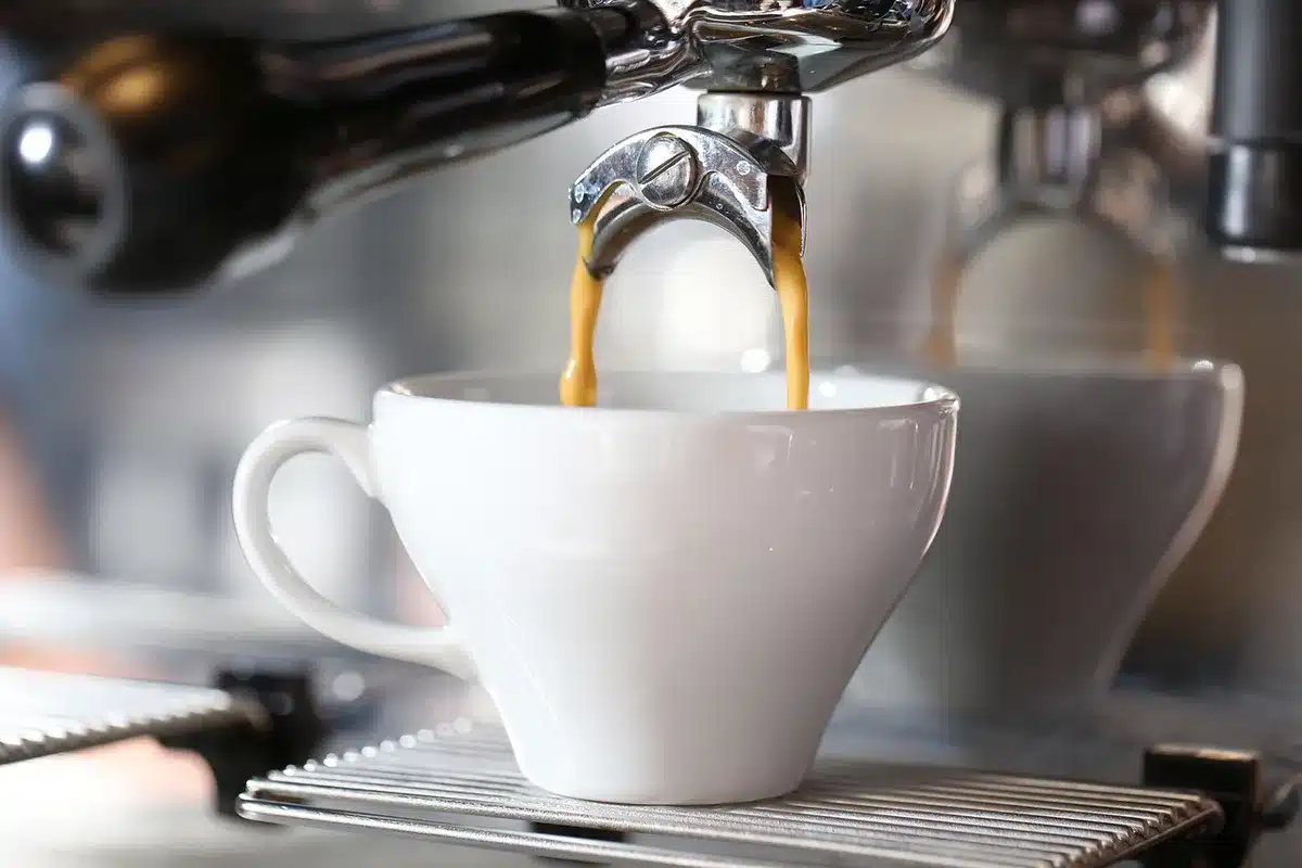 Barista-style pour of milk into a coffee cup with capsules and beans on a windowsill