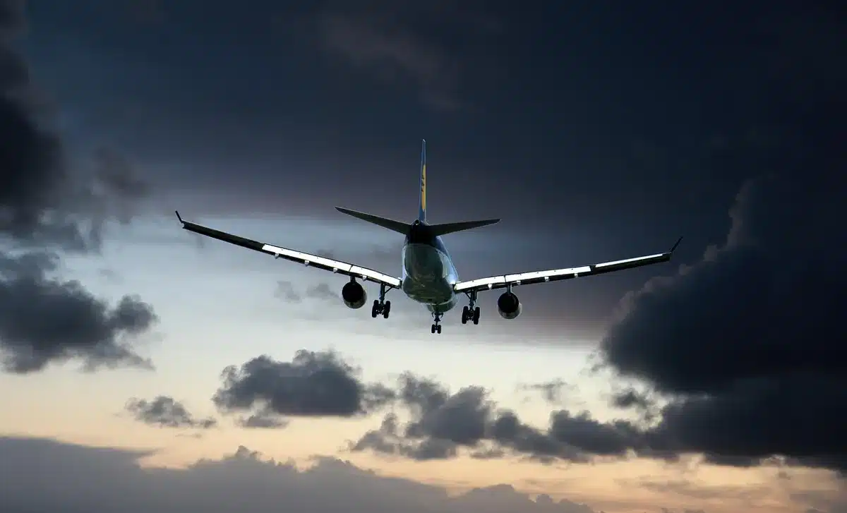 Passengers reacting inside a daytime airplane cabin as overhead panels loosen