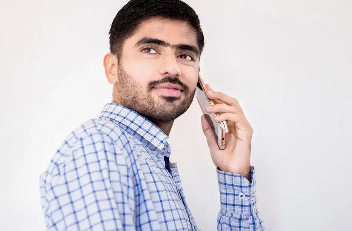 Hand holding phone showing a banking app while another hand points