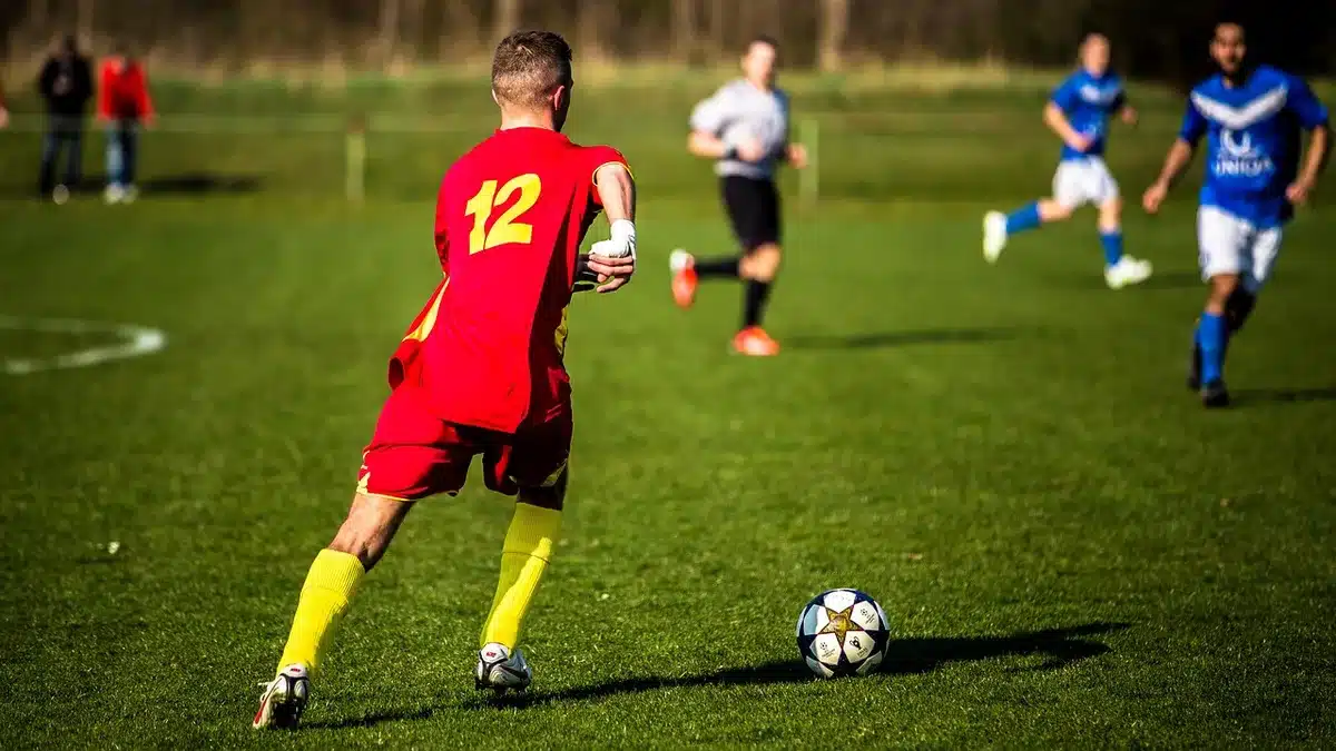 Two midfield players contesting a ball on a grassy pitch