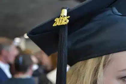 Student in gown holding degree with confetti in a university hall