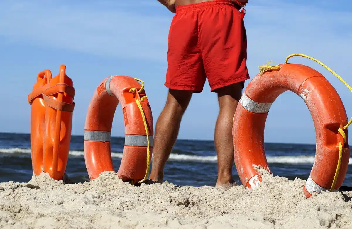 Lifeguard on paddleboard and responders attending on sandy beach