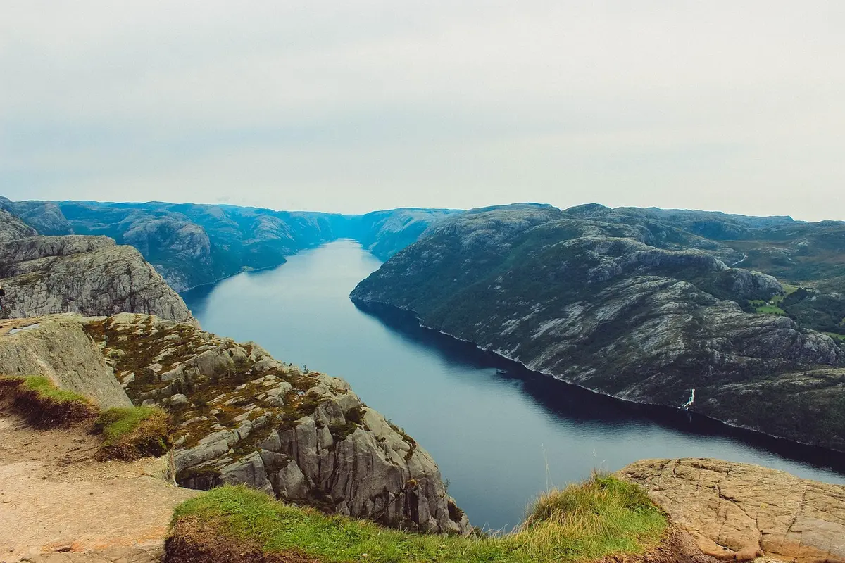 Hiker on mountain trail overlooking bright fjord landscape in Arctic summer daylight