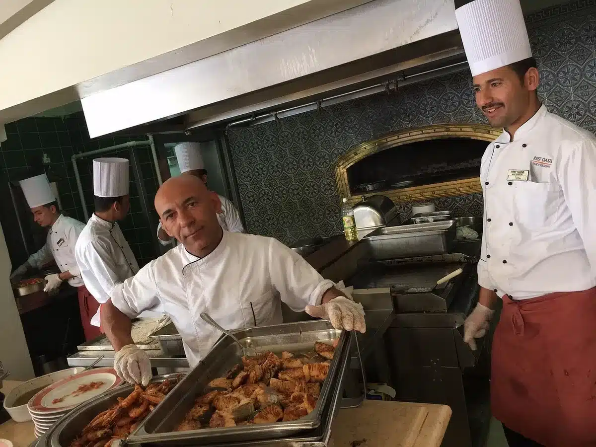 Chef clasping hands in a bright restaurant kitchen