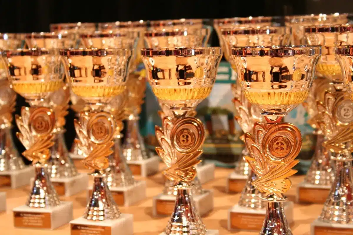 Officials and hosts at an awards ceremony stage receiving a trophy