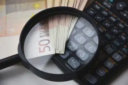 Hands holding a household energy bill on a sunny kitchen table with a calculator