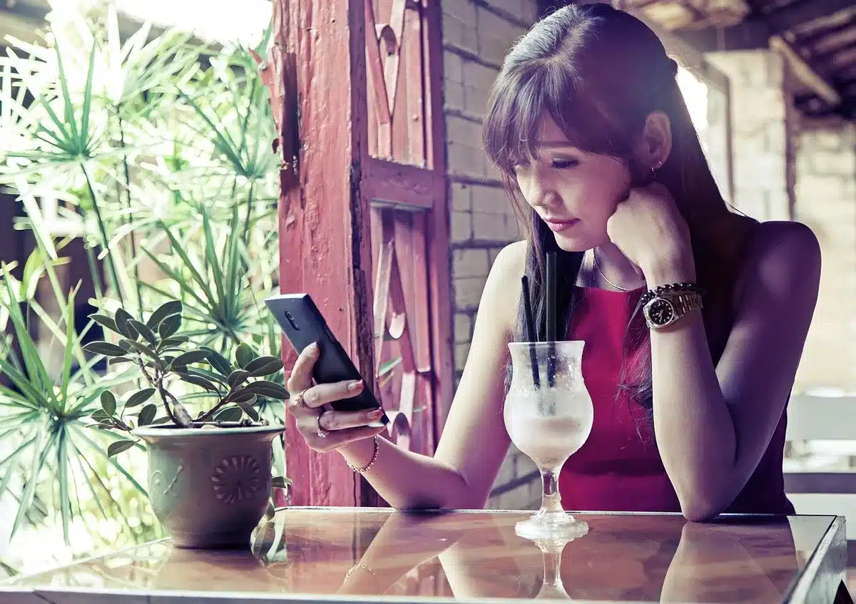 Hands holding a phone showing social media messages on a bright screen