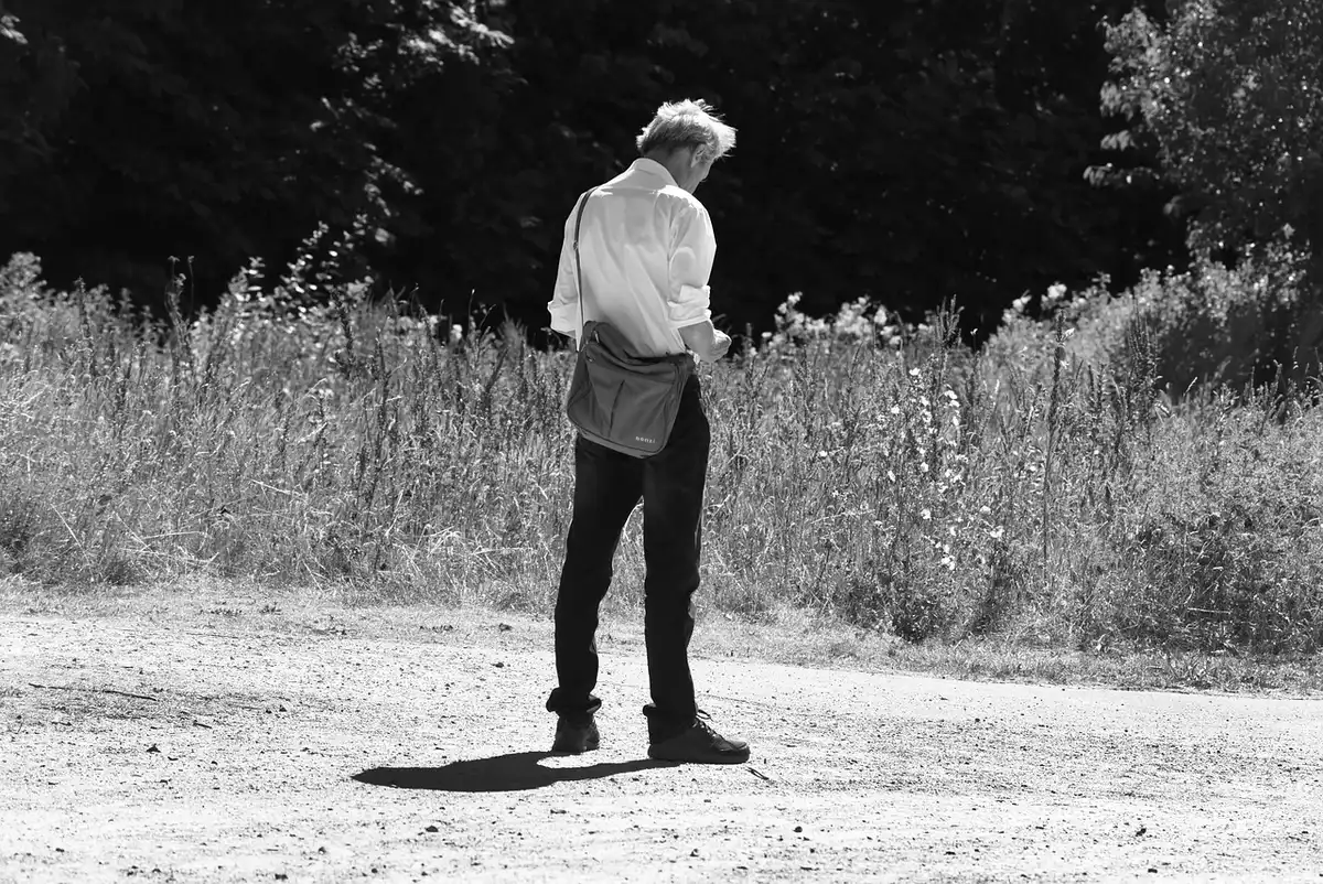 Person looking at phone footage on a pavement beside a quay