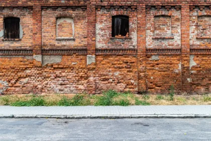 Daytime street of boarded urban buildings with a worker and paperwork visible