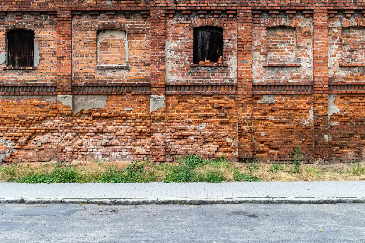 Daytime street of boarded urban buildings with a worker and paperwork visible