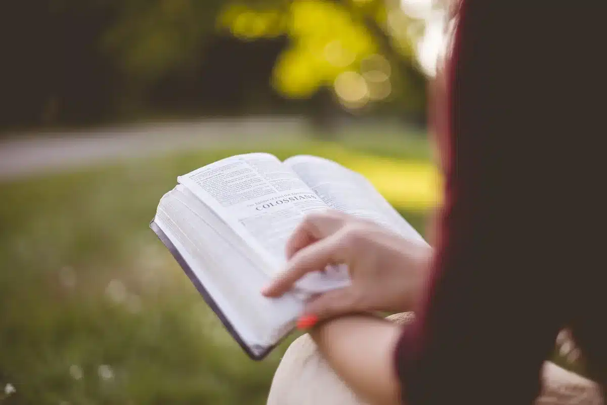 Close-up of hands holding an old book suggestive of a spellbook on a table