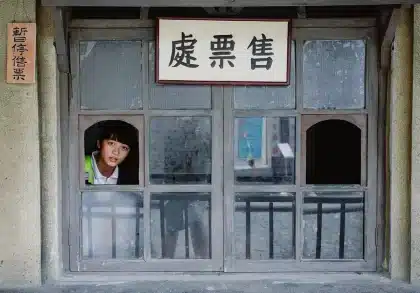 People queuing outside a cinema entrance in daylight, holding tickets