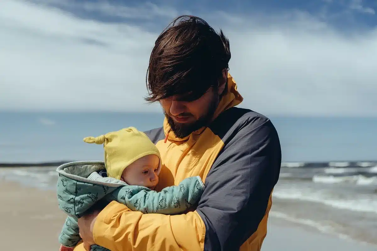 Father holding a newborn at home by a bright window