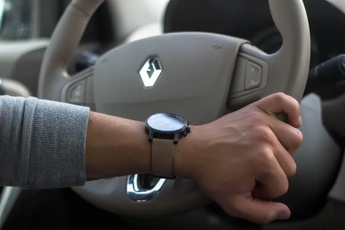 Hands on steering wheel inside a car in daylight, hinting at youth