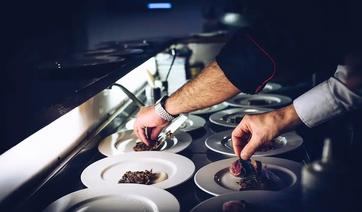 Chef's hands plating a dish in a bright kitchen