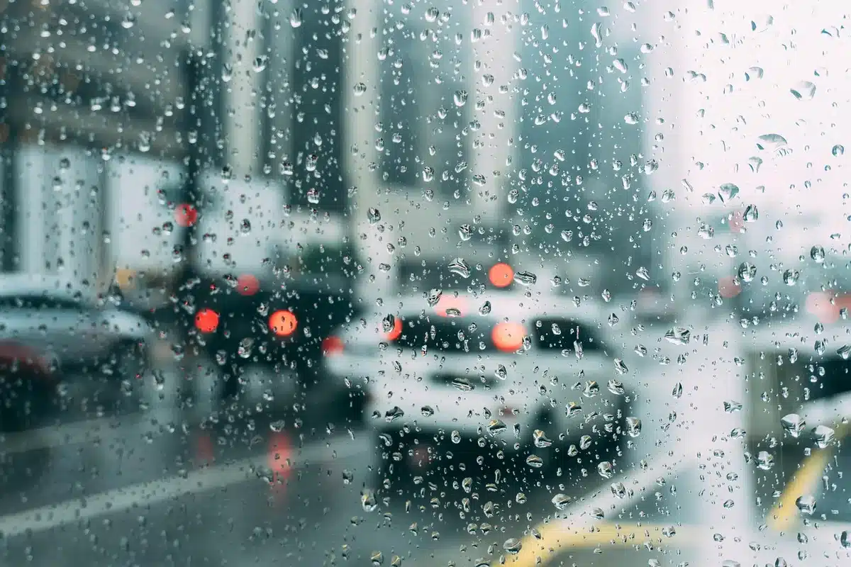 Car driving through a rain-swept country road with pooled water